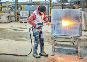Flammen einer Abdeckplatte für den Viadukt Val Tisch; diese Oberflächenbearbeitung dient dazu, eine bessere Haftung des Natursteins mit der Betonoberfläche des neuen Schottertrogs zu erzielen. (Foto: Robert Stadler)